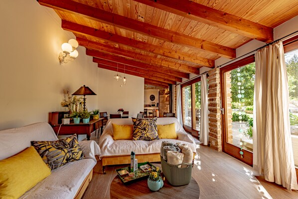 Une pièce chaleureuse avec un plafond en bois, un canapé, une table à manger et une fenêtre avec des rideaux.