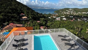 A rooftop pool with a view of a coastal town and hills. - Le Turquoise (Les Trois-Îlets)