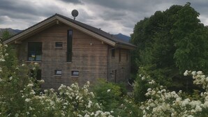 Una casa de madera con techo inclinado, antena parabólica y un pequeño balcón.