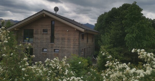 Et træhus med skråt tag, parabolantenne og en lille balkon.