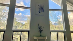 Une pièce dotée de grandes fenêtres, d’un plafond blanc et d’un tableau encadré accroché au mur.