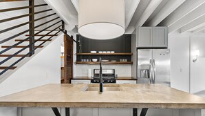Eine moderne Küche mit Kochinsel, Edelstahlgeräten und einer Holztreppe.