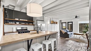 Eine moderne Küche mit einer zentralen Kochinsel, Barhocker und einem Essbereich mit Sofa und Tisch.