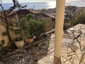 A rooftop terrace with a tiled floor, potted plants, and a view of the sea. - Terrace with stunning sea view and pergola with vines (Menton)