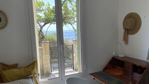 Un dormitorio con una ventana grande, un escritorio, una silla y una cama con almohadas.