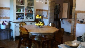 Un comedor con una mesa redonda de madera, sillas, una araña y un horno de ladrillo.