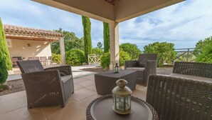 An outdoor patio with wicker furniture, a lantern, and a view of the surrounding garden and sky. - Villa Lou Coulabio - Stay in Provence with Private Pool and Panoramic View (Tourtour)