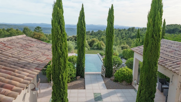 A rooftop pool area with a clear view of the surrounding landscape, including tall cypress trees and distant hills. - Villa Lou Coulabio - Stay in Provence with Private Pool and Panoramic View (Tourtour)
