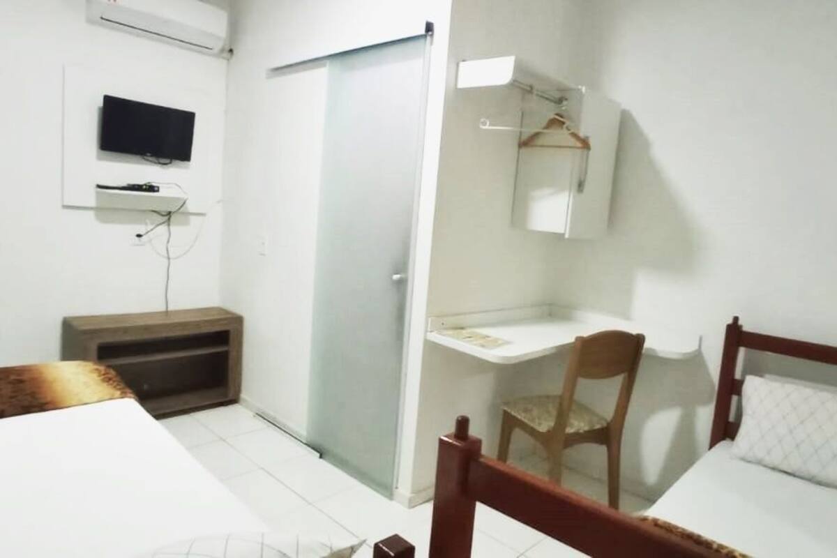 A room with a bed, a desk, a chair, a TV, and a wardrobe.