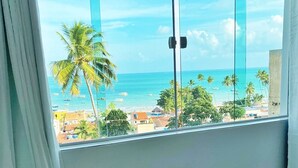 Un balcón con vista a la playa y palmeras.
