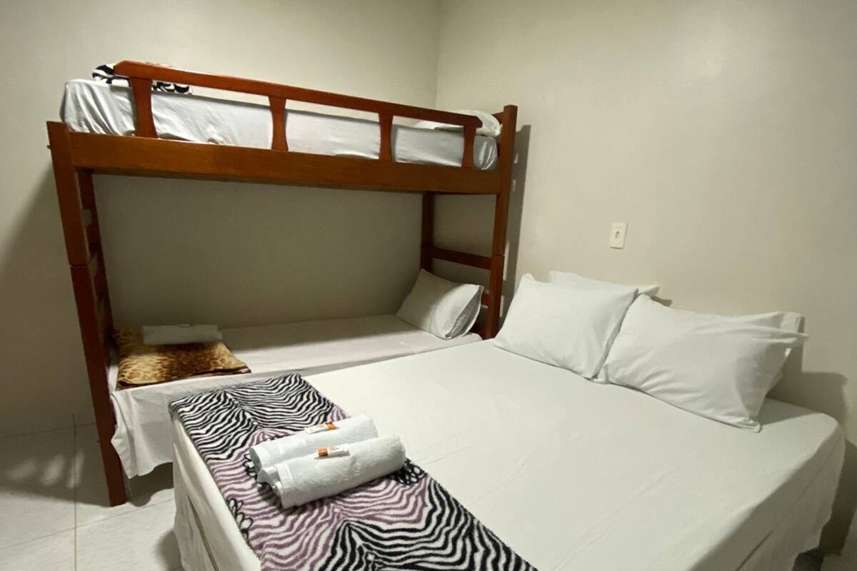 A bunk bed with a zebra-patterned blanket and towels, a wooden headboard, and white bedding.