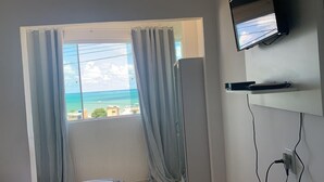 Habitación con un ventanal grande, un televisor de pantalla plana montado en la pared y un enchufe.