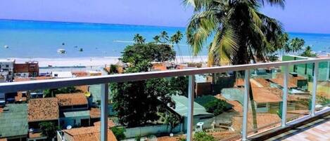 Un balcón con vista a una playa y palmeras.