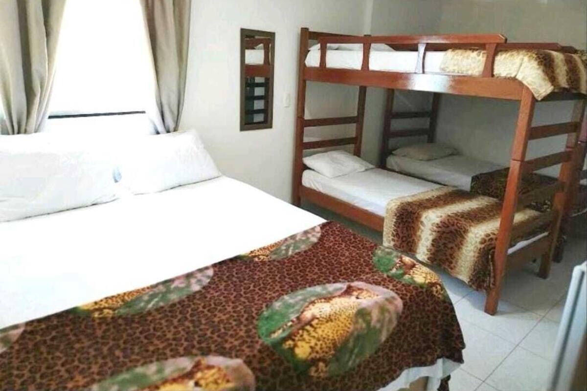 A room with a bunk bed, a single bed, and a window with curtains.