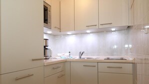 Una cucina moderna con mobili bianchi, elettrodomestici in acciaio inossidabile e rivestimento a mosaico.