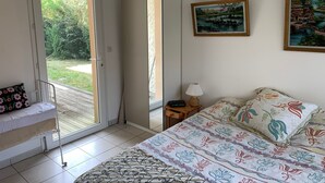 Een slaapkamer met een bed, nachtkastje, lamp, spiegel en raam.