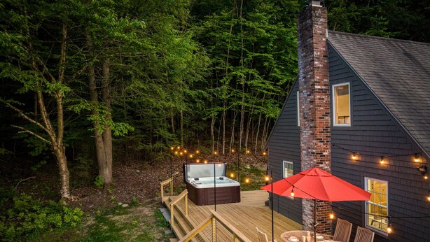 A cabin with a hot tub on a wooden deck, surrounded by trees. - Hike & Bike Stowe | 7 Min to Town | AC | Hot Tub (Stowe)
