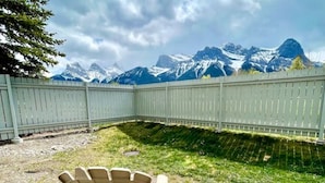 En terrasse med Adirondack-stole med udsigt til et bjerg, omgivet af et hvidt hegn.