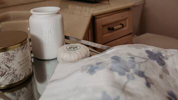 Een badkamer met een beige wastafel, een witte vaas met de tekst 'BAIN DE LUXE', een klein rond potje en een handdoek met bloemenprint op een dienblad.
