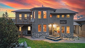 A two-story house with a stone foundation, a balcony, and a sign reading "Rocky Mountain View." - RockyMountainView BnB (Entrance)