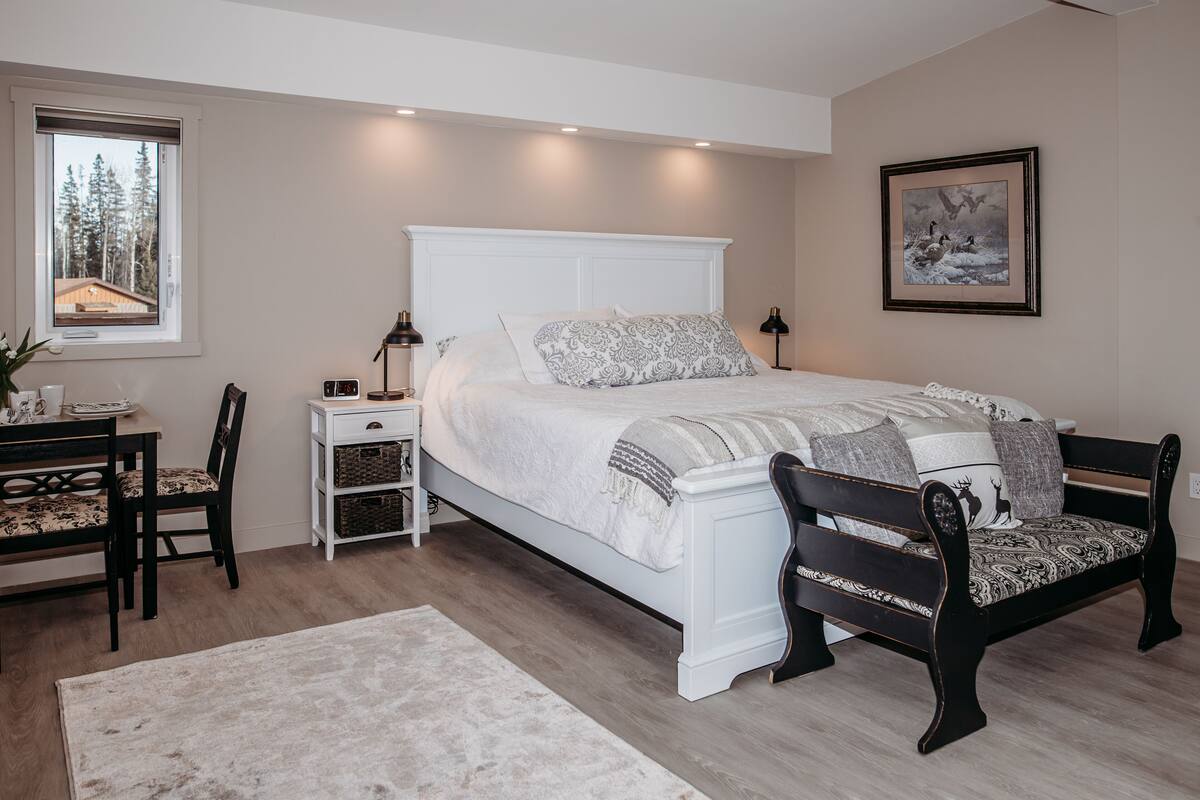A bedroom with a bed, bedside tables, a chair, a desk, and a window.