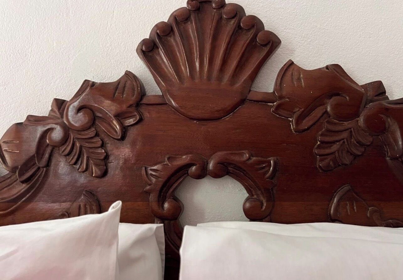 Cabecera de madera con diseños florales y de conchas talladas.