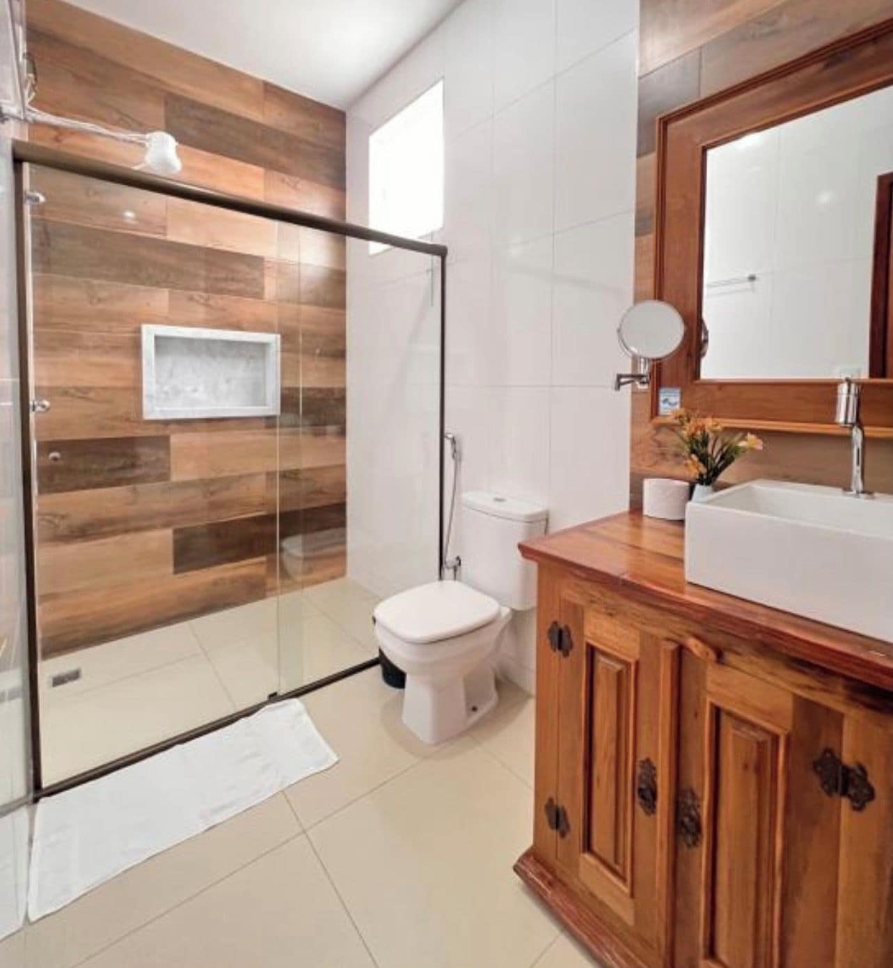 A modern bathroom with a glass-enclosed shower, a white toilet, and wooden cabinetry.