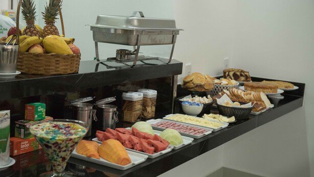 Un bufé con diferentes opciones de comida, como frutas, sándwiches y una ensalada.