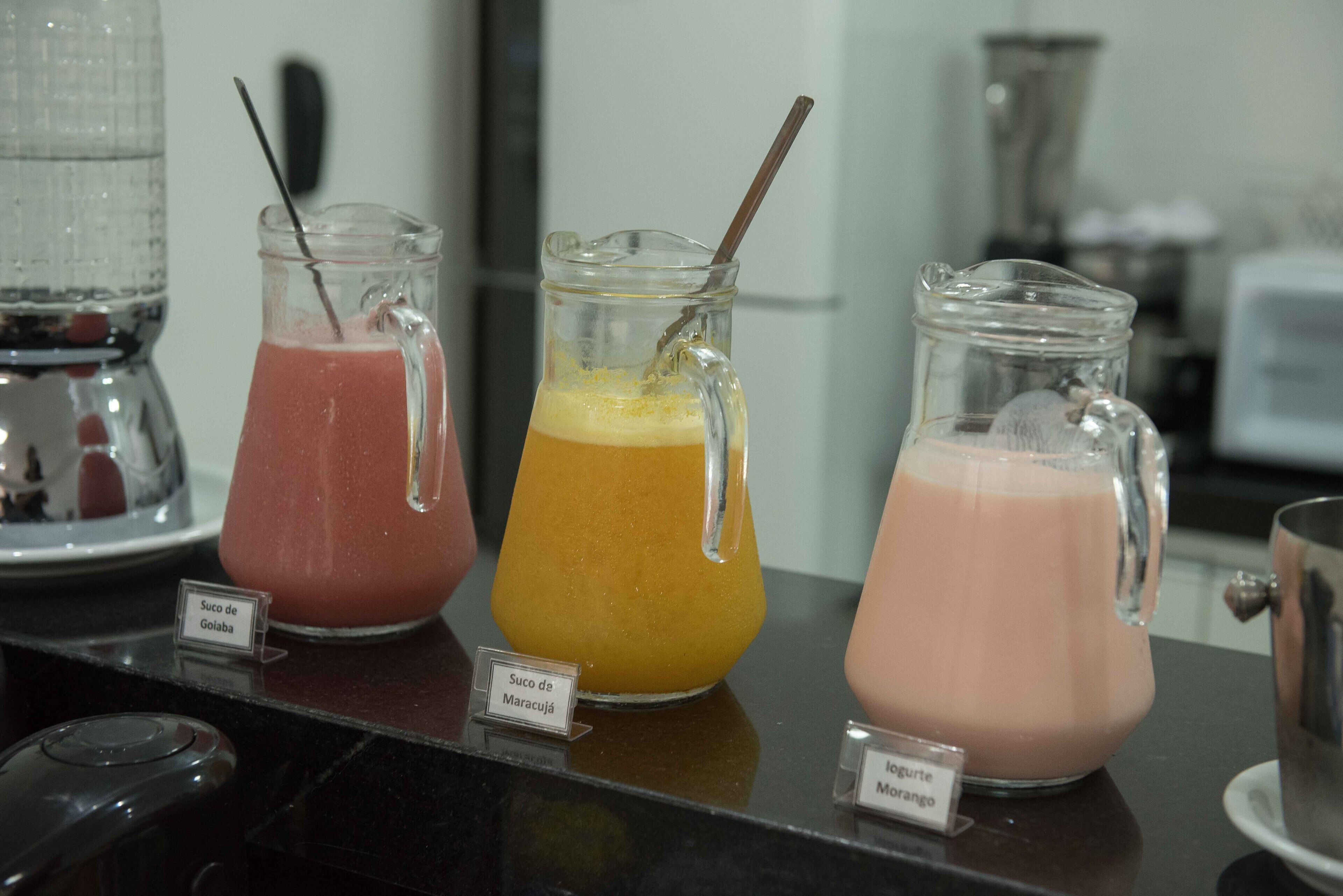 Three pitchers of different colored beverages on a counter with labels.