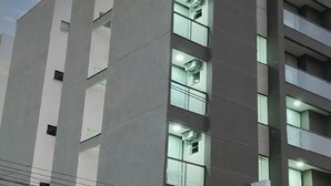 Un moderno edificio de hotel con un llamativo letrero 'HOTEL' en la fachada, varios balcones y banderas en el techo.