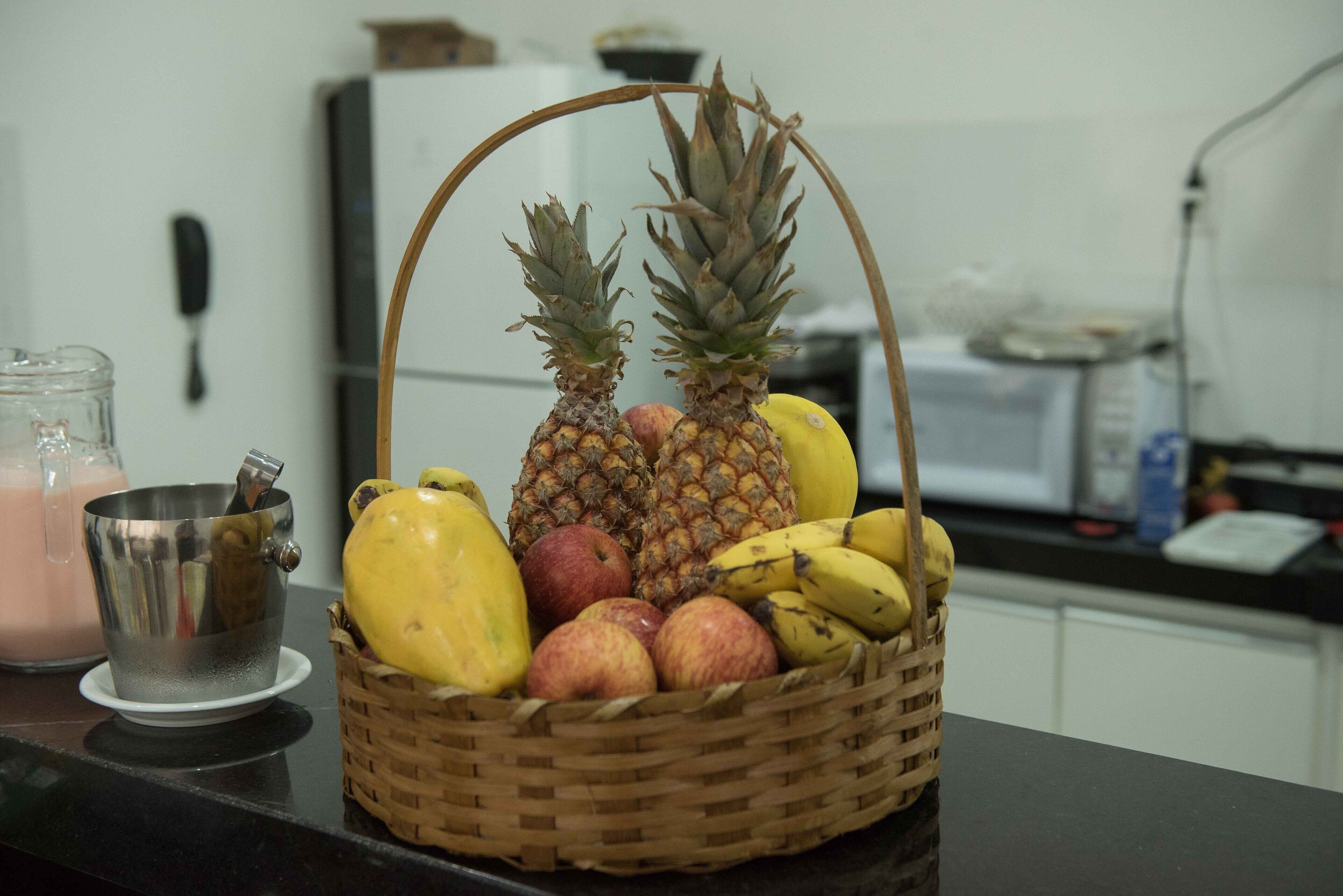 Una encimera de cocina con una cesta de frutas que contiene plátanos, manzanas y piñas.