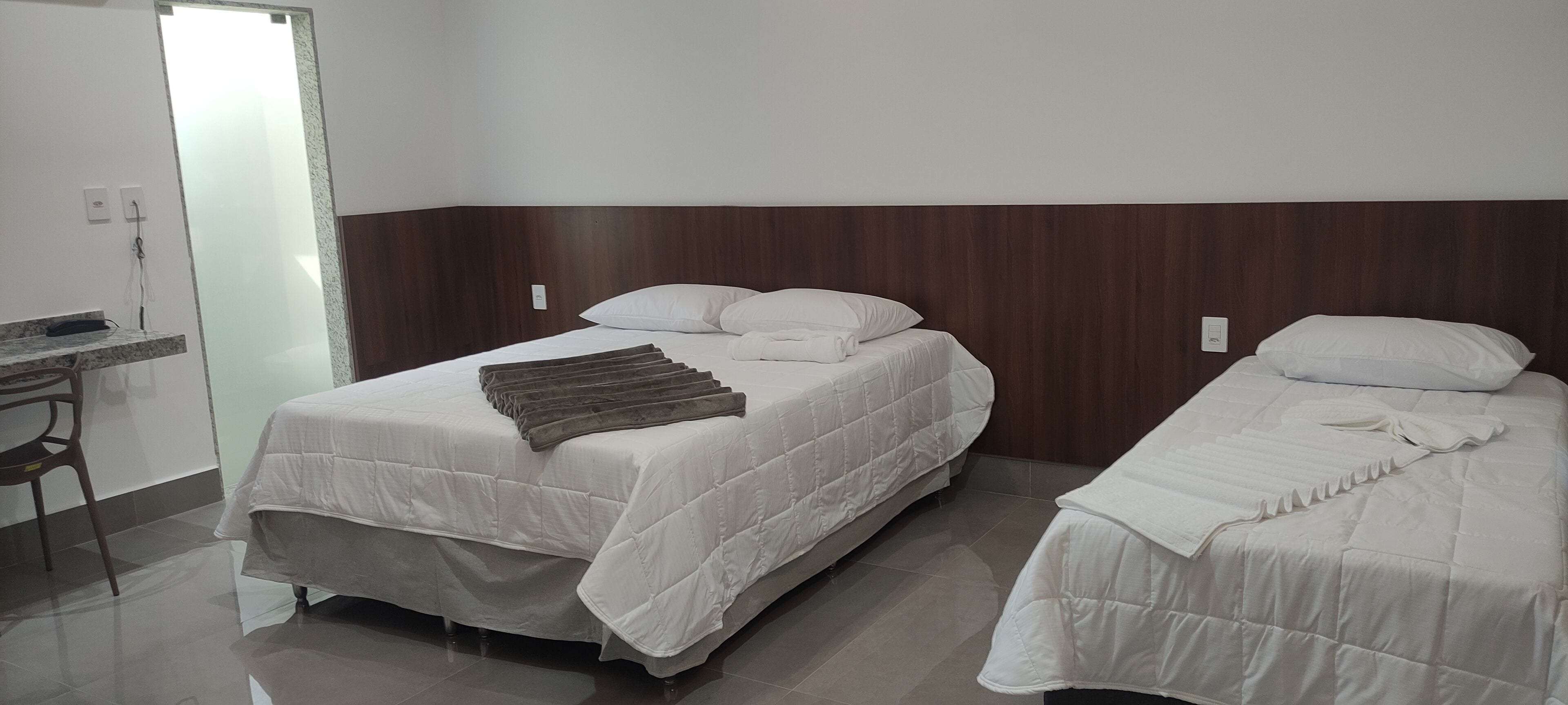 Una habitación de hotel con dos camas, un cabecero de madera, un escritorio pequeño y un espejo.