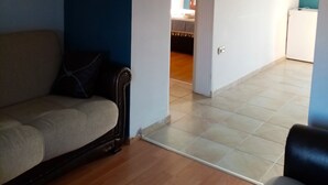 Una sala de estar con un sofá, una silla y un pasillo que lleva a otra habitación.