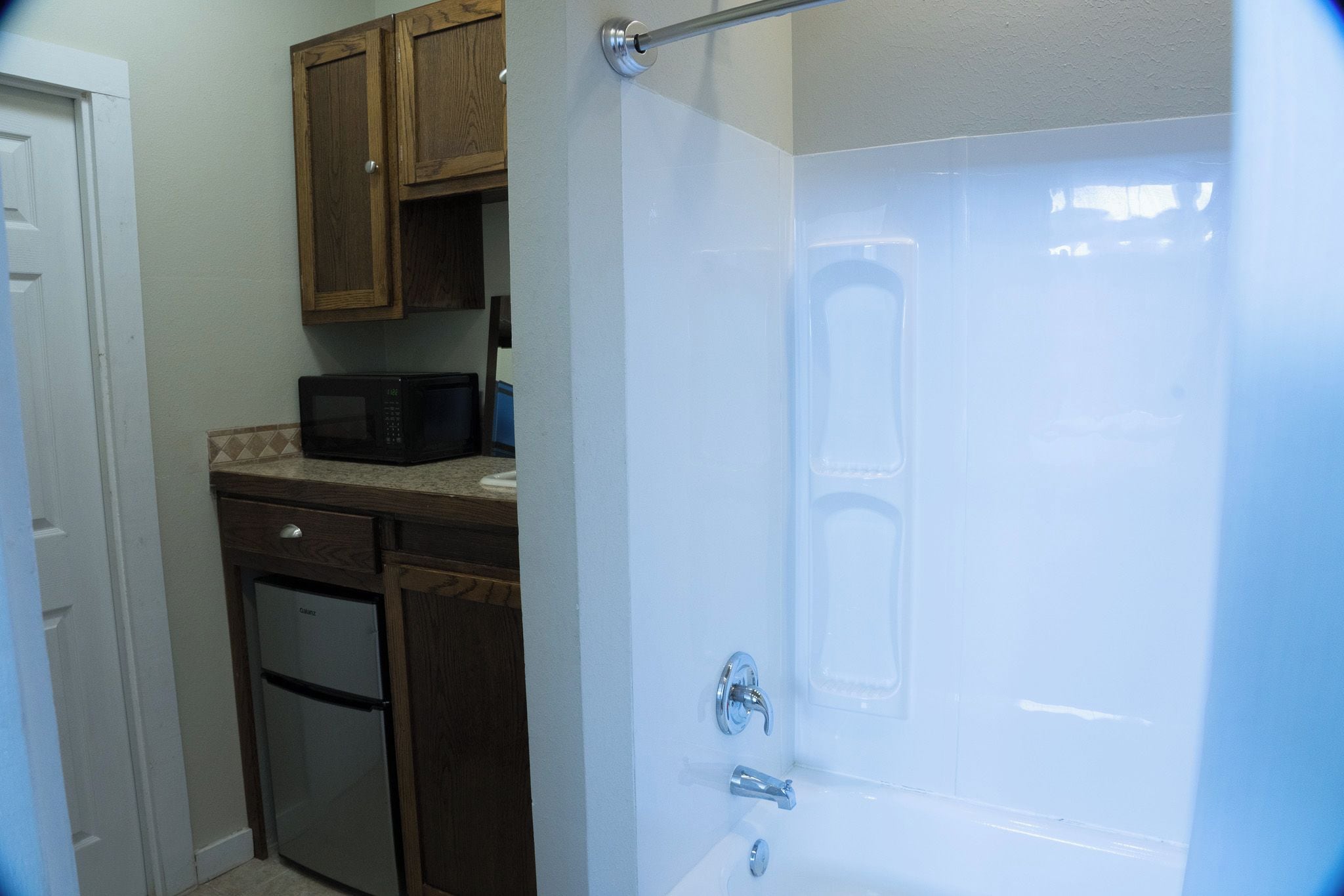 A kitchen with wooden cabinets, a microwave, and a refrigerator.