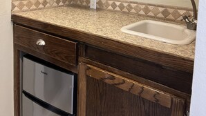 Una cocina con armarios de madera, encimera de granito, lavavajillas de acero inoxidable y un lavabo con grifo.