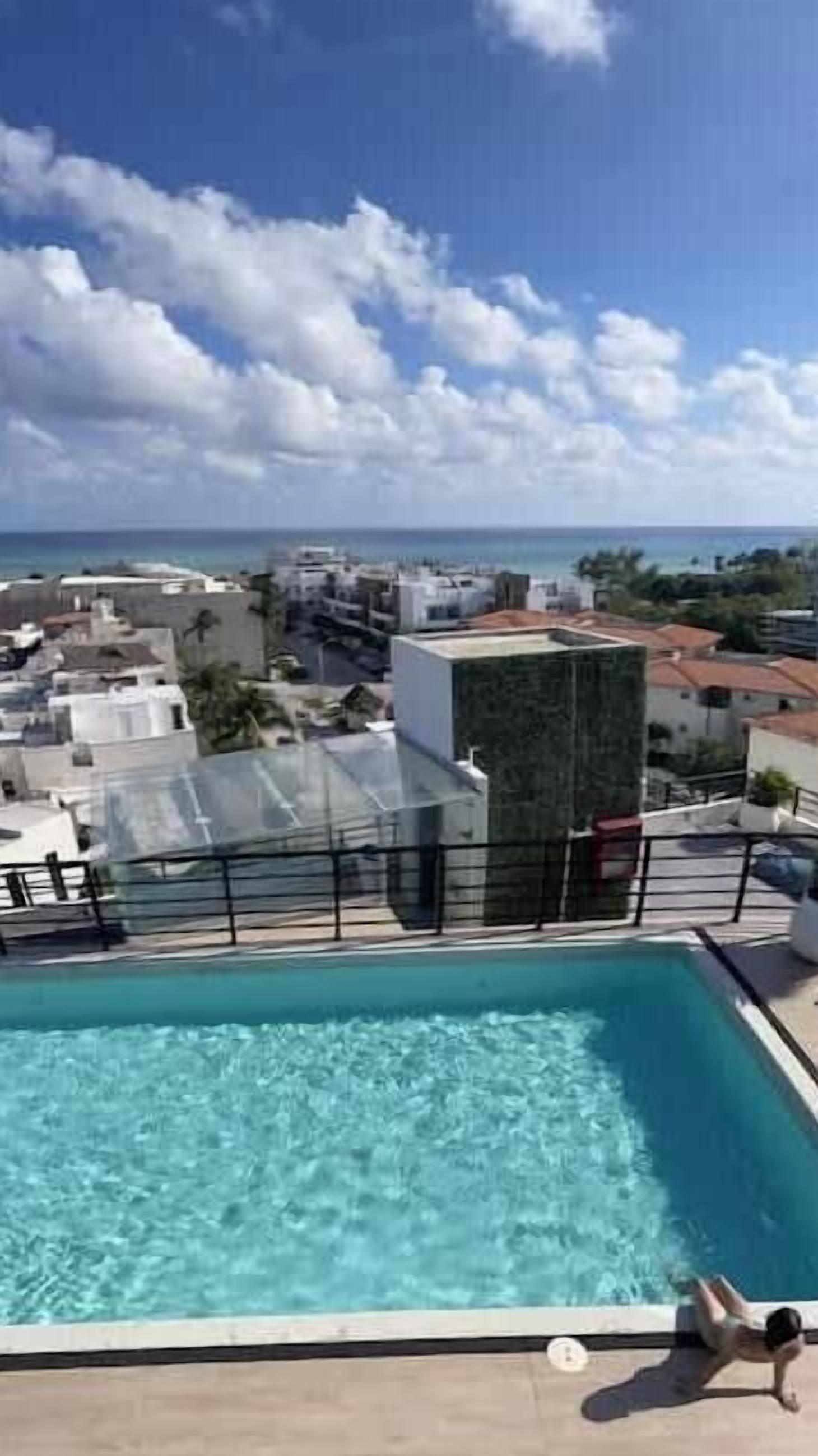 A rooftop pool with a view of the city and ocean.