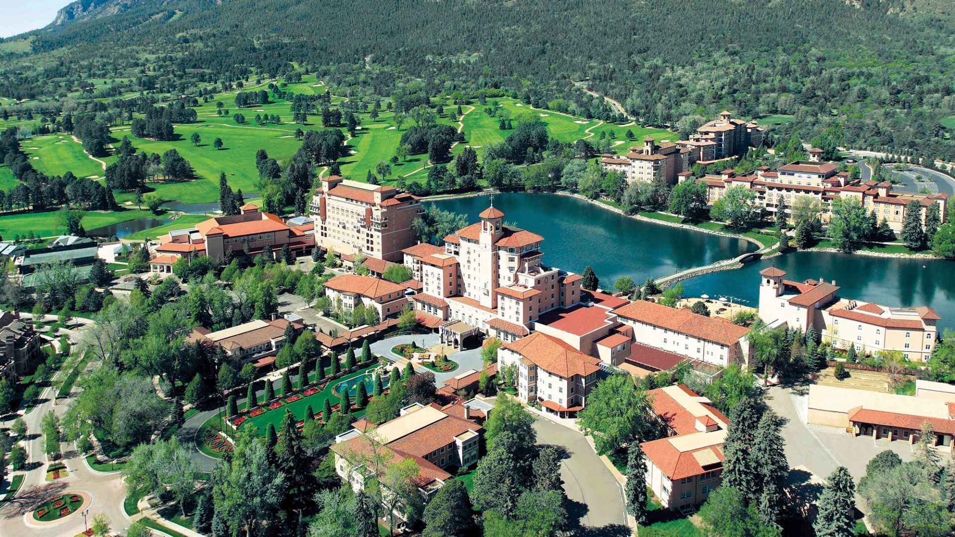 A large hotel complex with multiple buildings, a central tower, and a lake.
