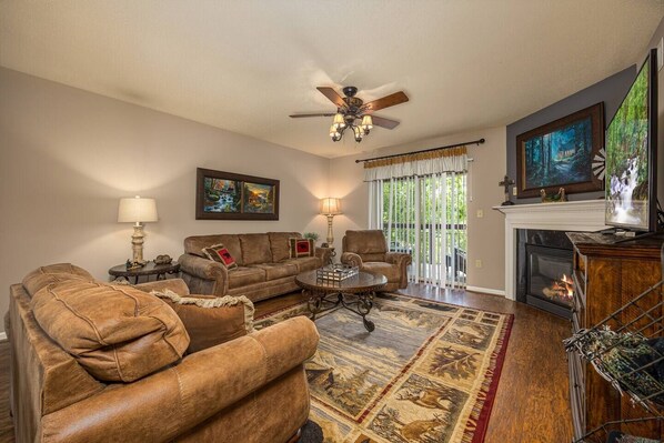 A living room with a fireplace, leather sofas, a coffee table, and a ceiling fan. - Riverside Retreat Close to Dollywood (Pigeon Forge)