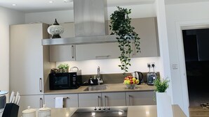 A modern kitchen with a central island, stainless steel appliances, and a large window. - Charming 3-bed Apartment in London (London)