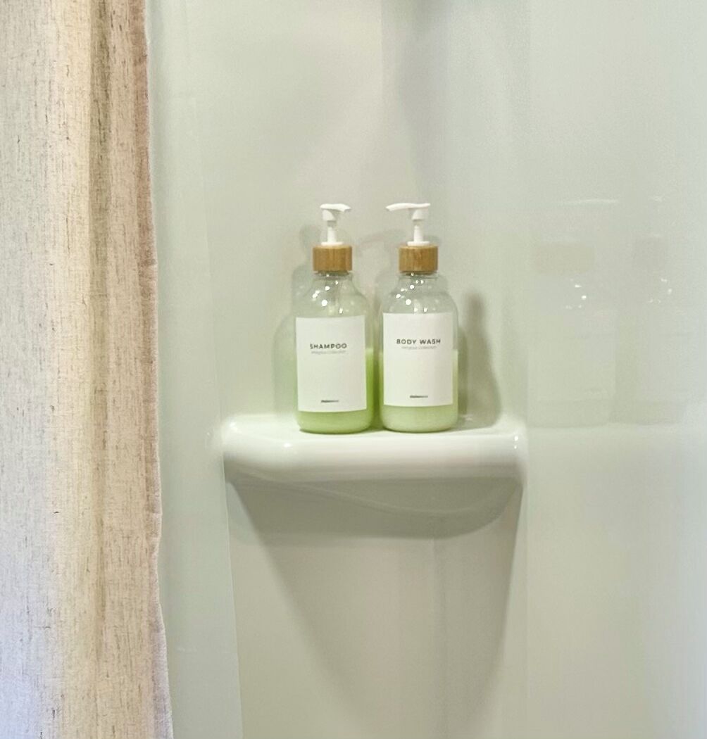 Two bottles of shampoo and body wash on a white shelf.