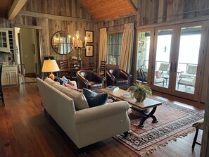 A cozy living room with a sofa, chairs, a coffee table, and a dining area with a chandelier.