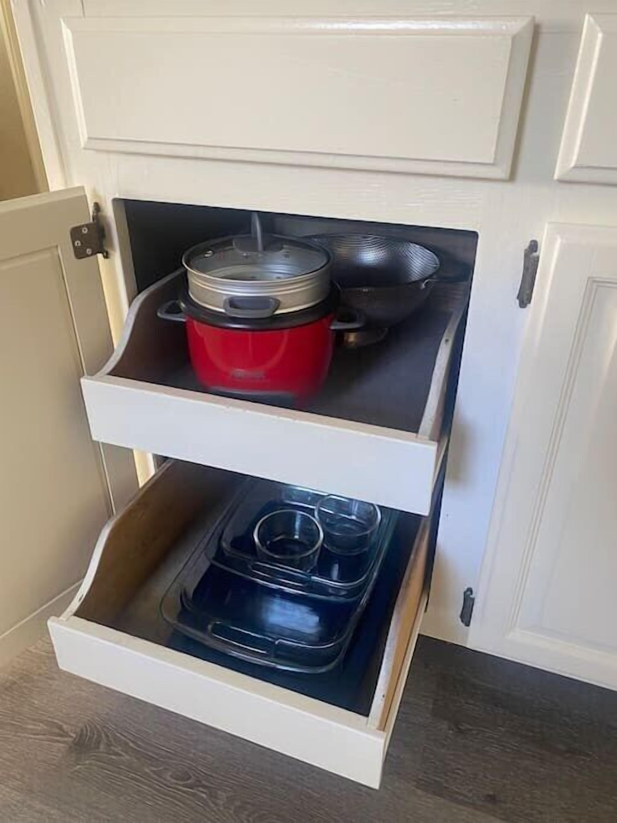 Ein Küchenschrank mit einem roten Topf auf der obersten Ablage und einer schwarzen Tablett auf der untersten Ablage.