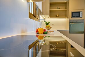 Une cuisine moderne dotée d’un plan de travail réfléchissant, d’un four encastré et d’un four à micro-ondes.