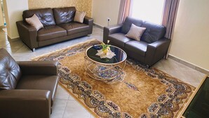 A living room with two brown leather sofas, a glass coffee table, and a patterned rug. - Stunning 2-bed Cozy Furnished Apartment in Nairobi (Nairobi)