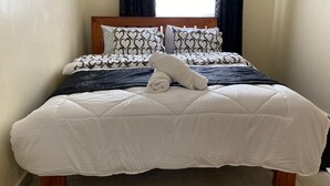 A neatly made bed with a white duvet, patterned pillows, and a folded towel on top. - Stunning 2-bed Cozy Furnished Apartment in Nairobi (Nairobi)