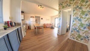 A spacious living area with a dining table and chairs, a kitchen with appliances, and a hallway with a door. - Beachfront/2br/garden/bbq/seaview/quietretreat (Mesolongi)
