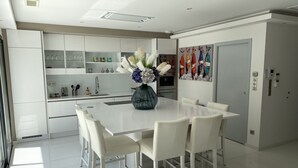 Una cocina moderna con armarios blancos, una isla grande con sillas y un florero con flores.