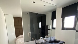 Un baño moderno con tocador doble, un espejo grande y zona de ducha separada.