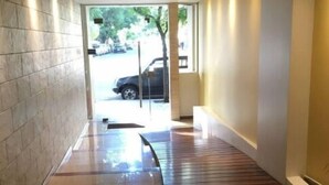 Un couloir doté d’un plancher en bois, de murs carrelés et d’une porte en verre donnant sur l’extérieur.