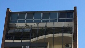 Un immeuble à plusieurs étages doté de grandes fenêtres, d’un balcon au deuxième étage et de climatiseurs installés à l’extérieur.